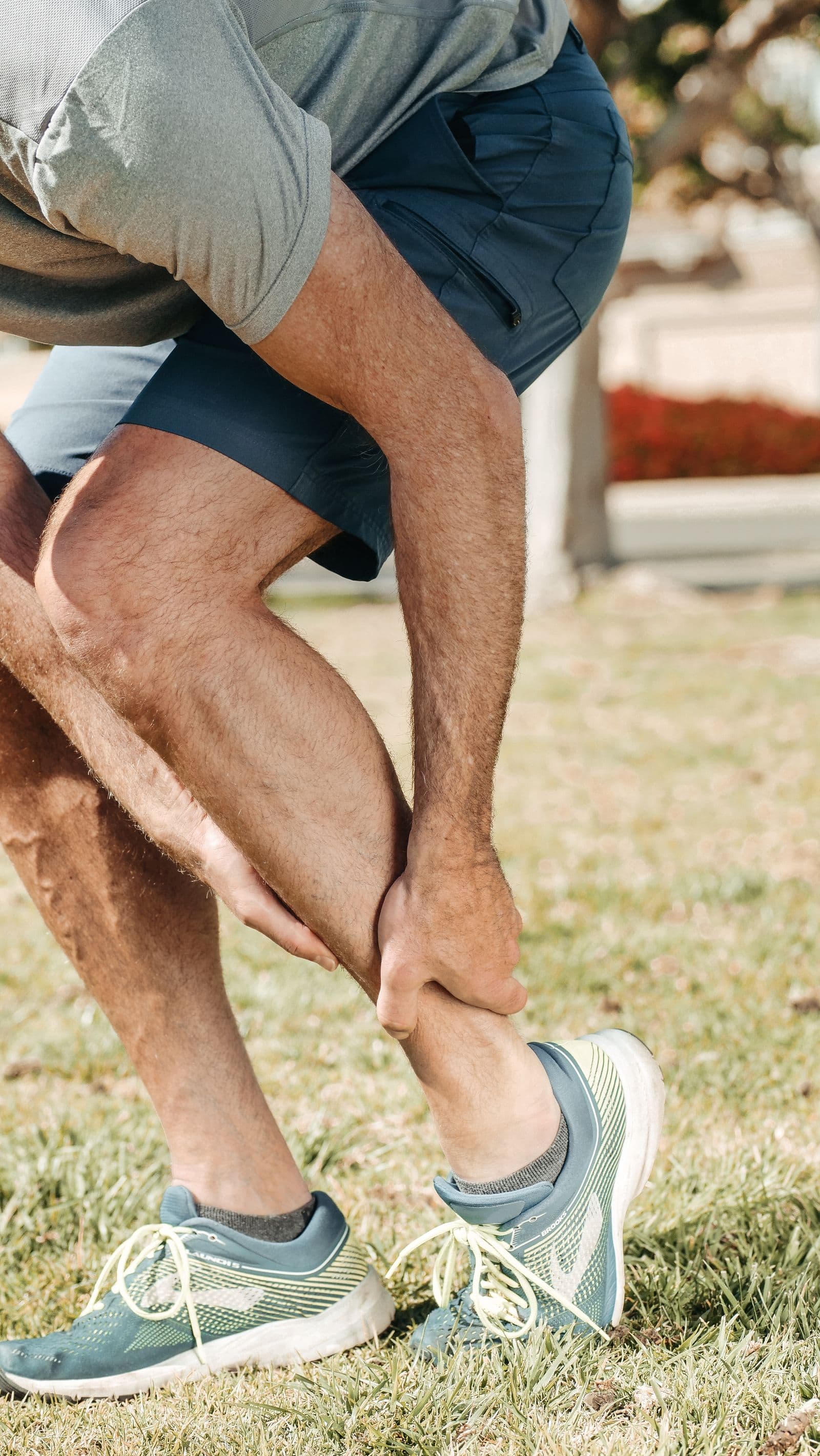 Athlete clutching their ankle in running shoes