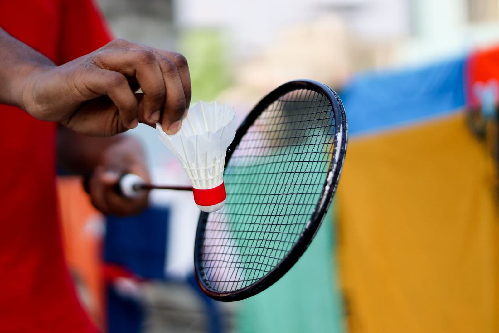 Close-up of a hand holding a shuttlecock and badminton racket