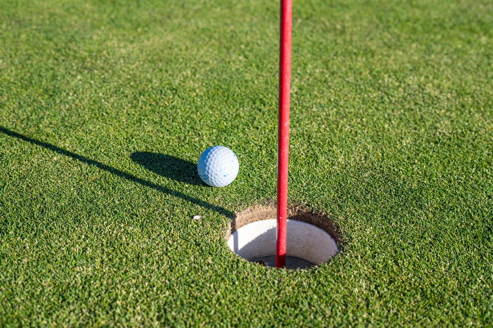Golf ball beside the flagstick on a green