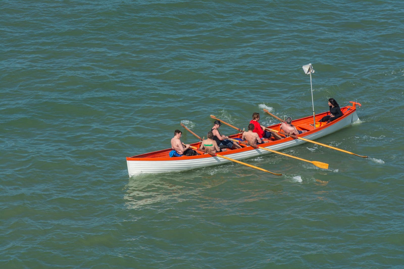 Aerial view of a crew rowing a wooden boat together