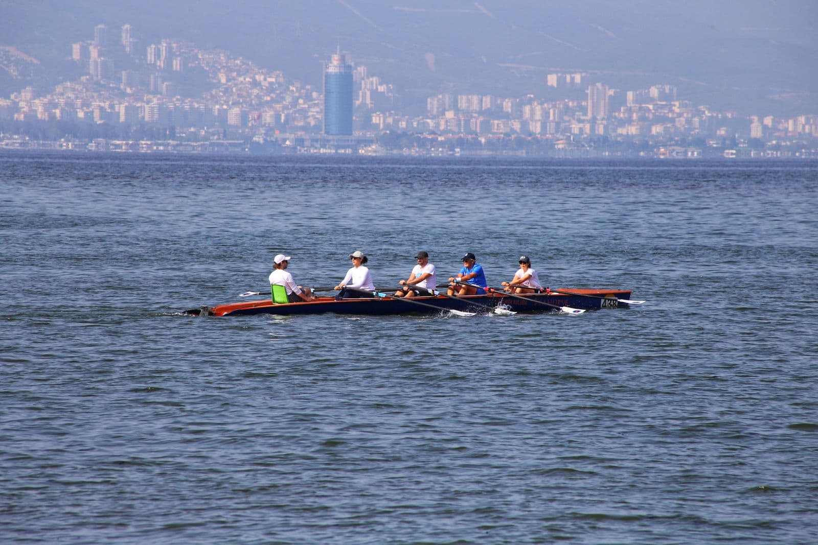 Four rowers sweeping in time across a bay