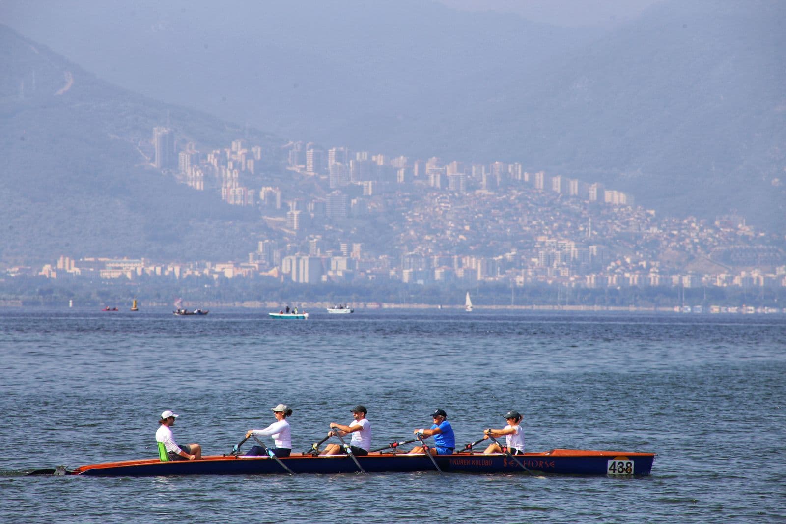 Sweep rowers pulling hard across a bay