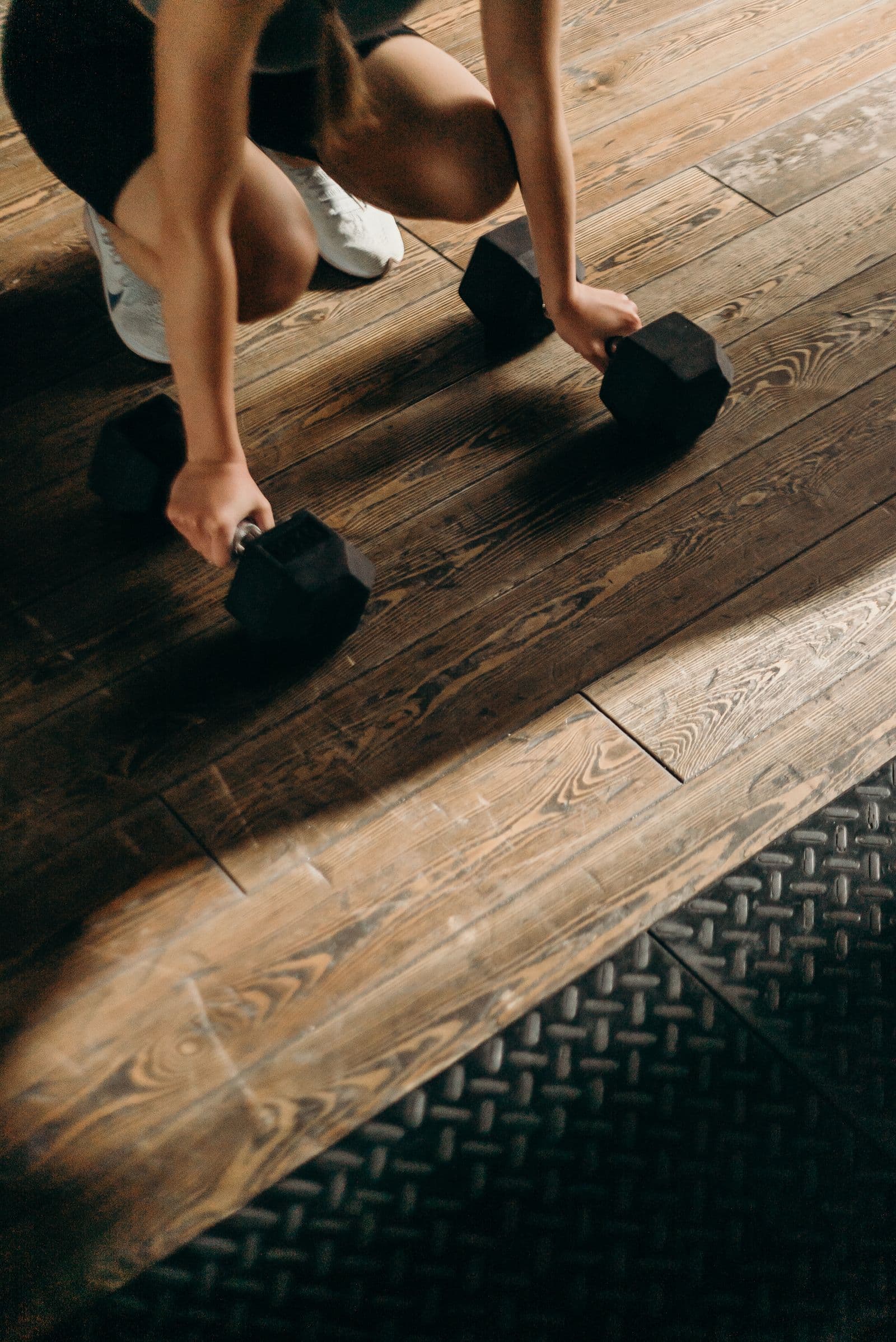 Athlete training with dumbbells on a gym floor