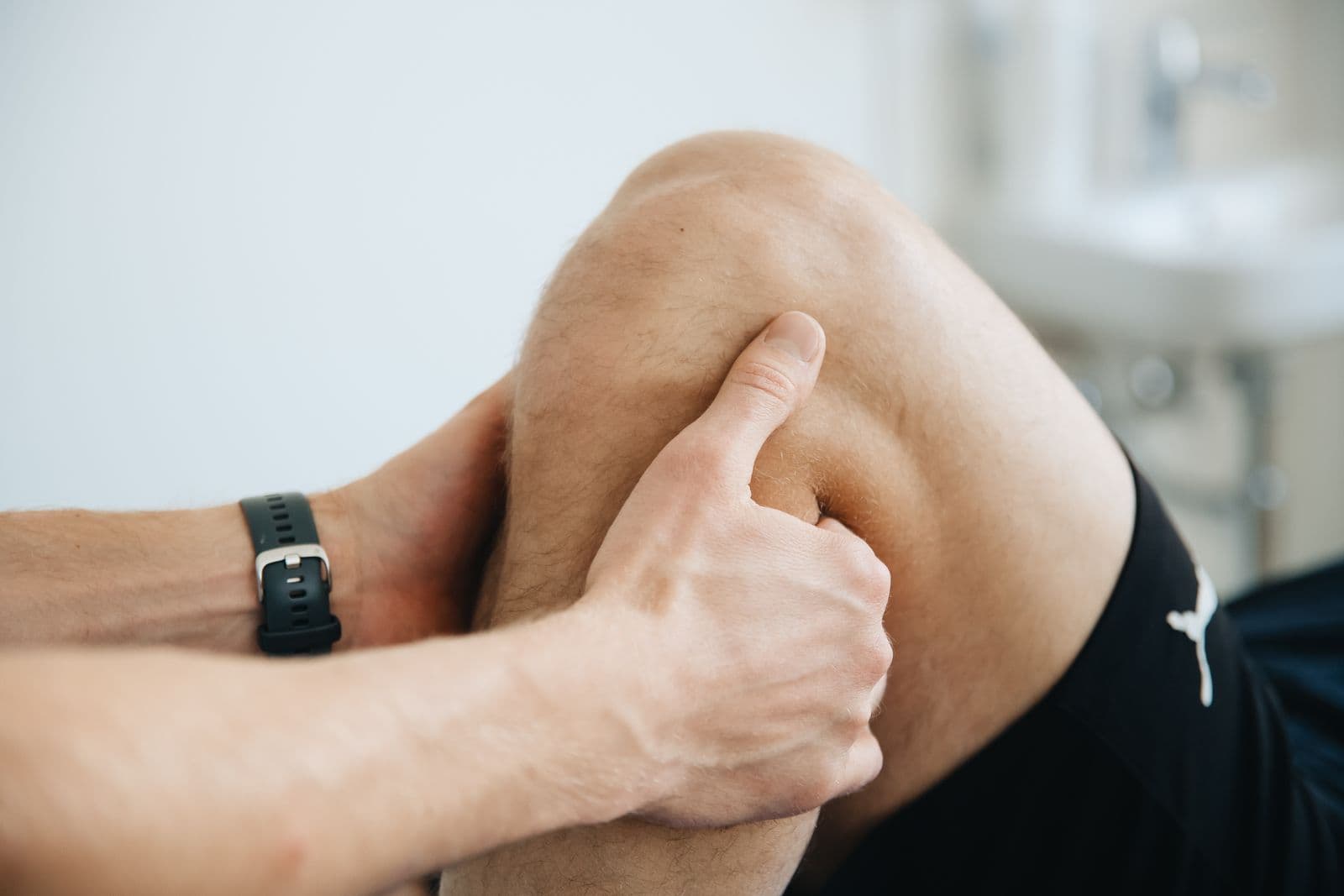 Physical therapist's hands assessing an athlete's knee
