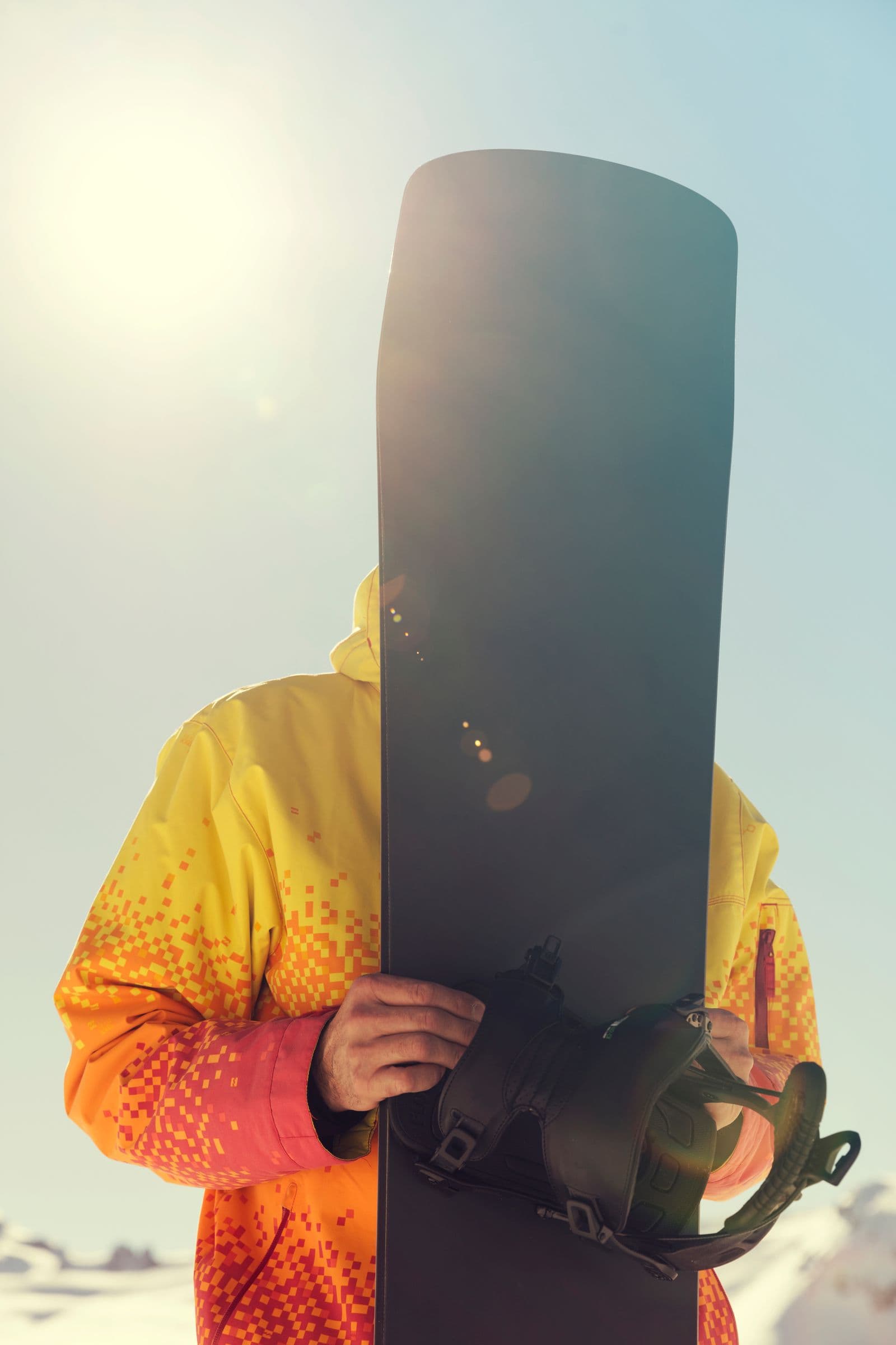 Snowboarder holding a board on a sunny slope
