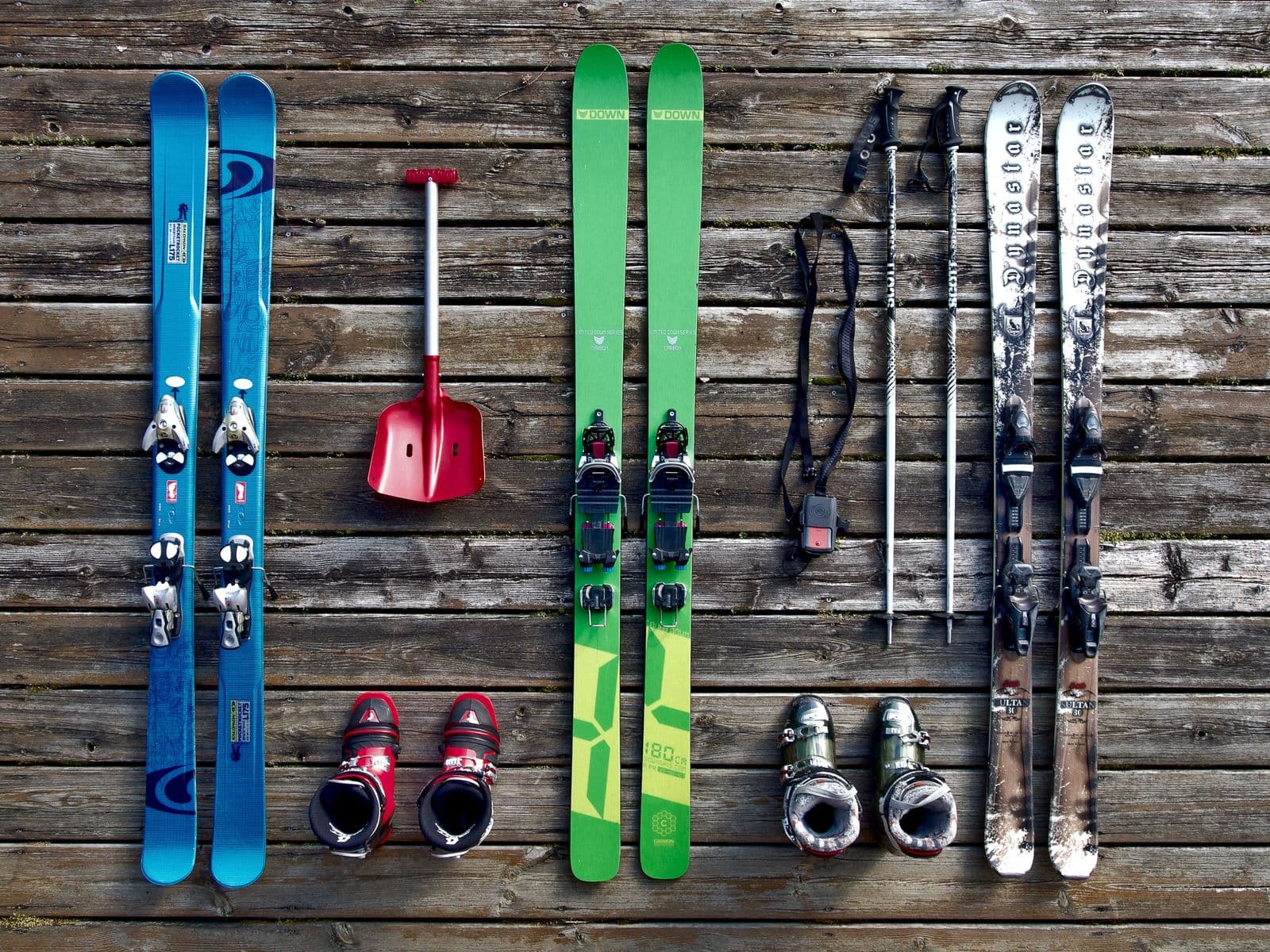 Ski boots, skis, and poles laid out on a wooden deck