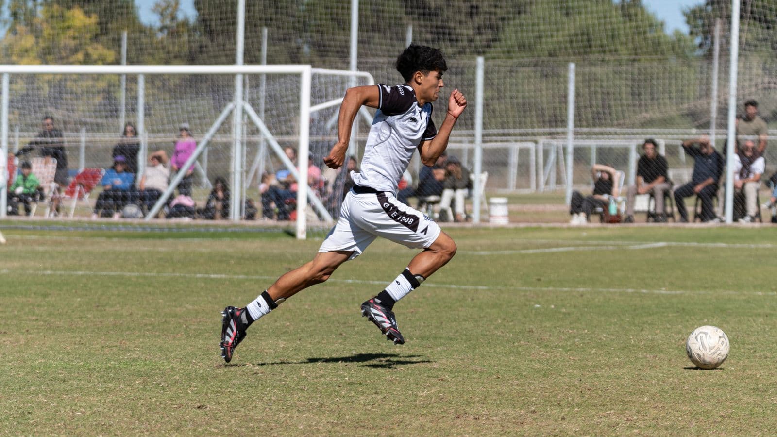 Soccer player running with the ball on a sunny pitch