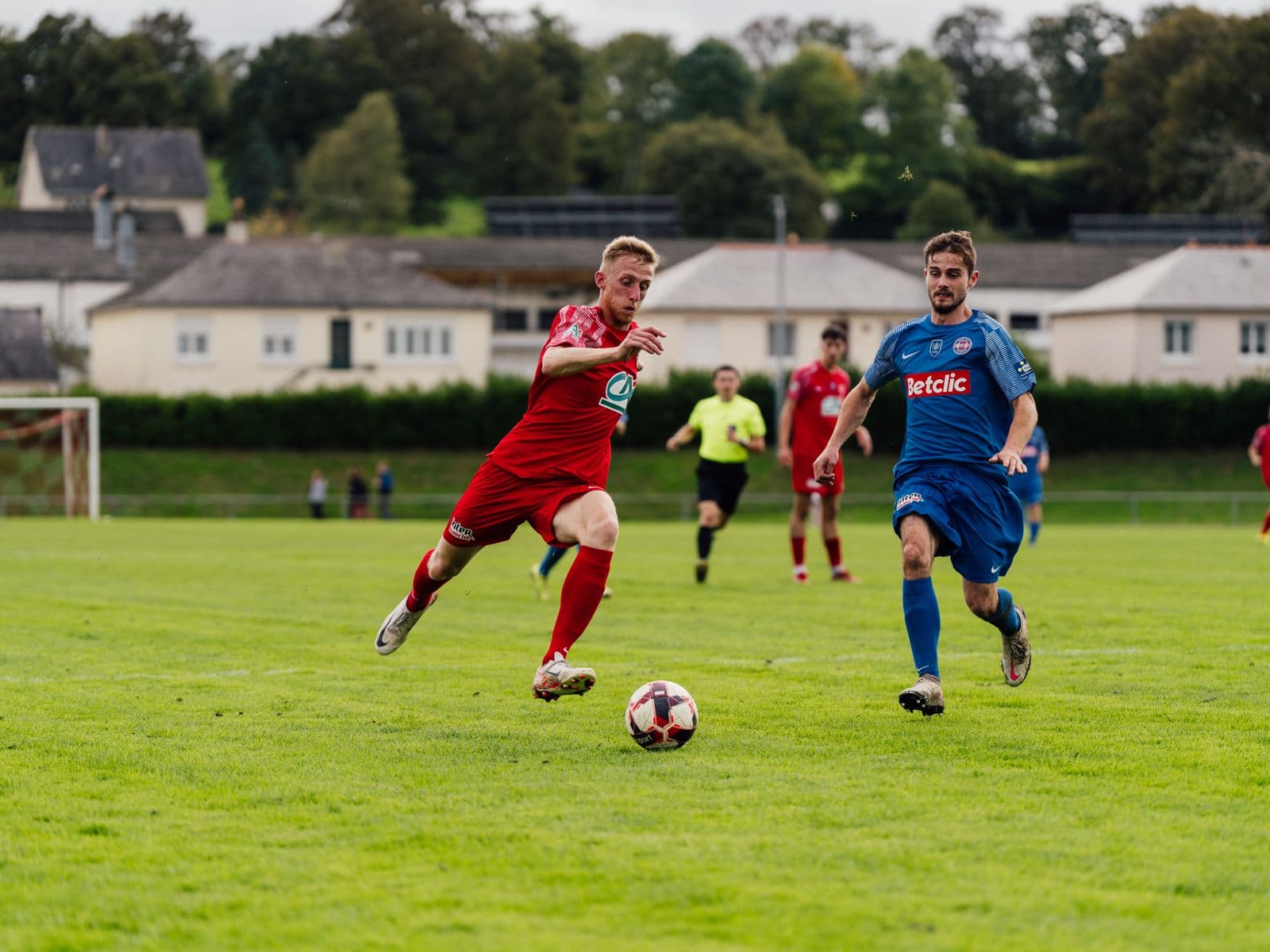 Adult players competing in a soccer match on a green pitch
