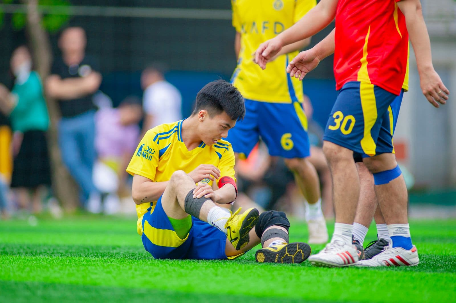 Amateur player sitting on the grass checking his leg