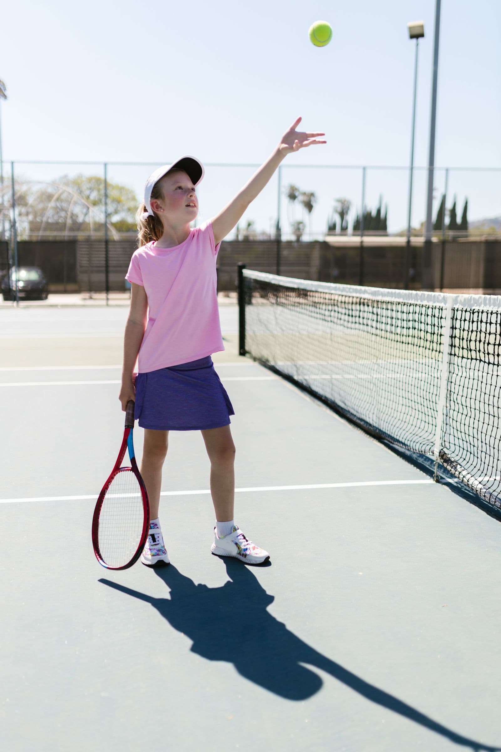 Young girl practicing her tennis serve on an outdoor court