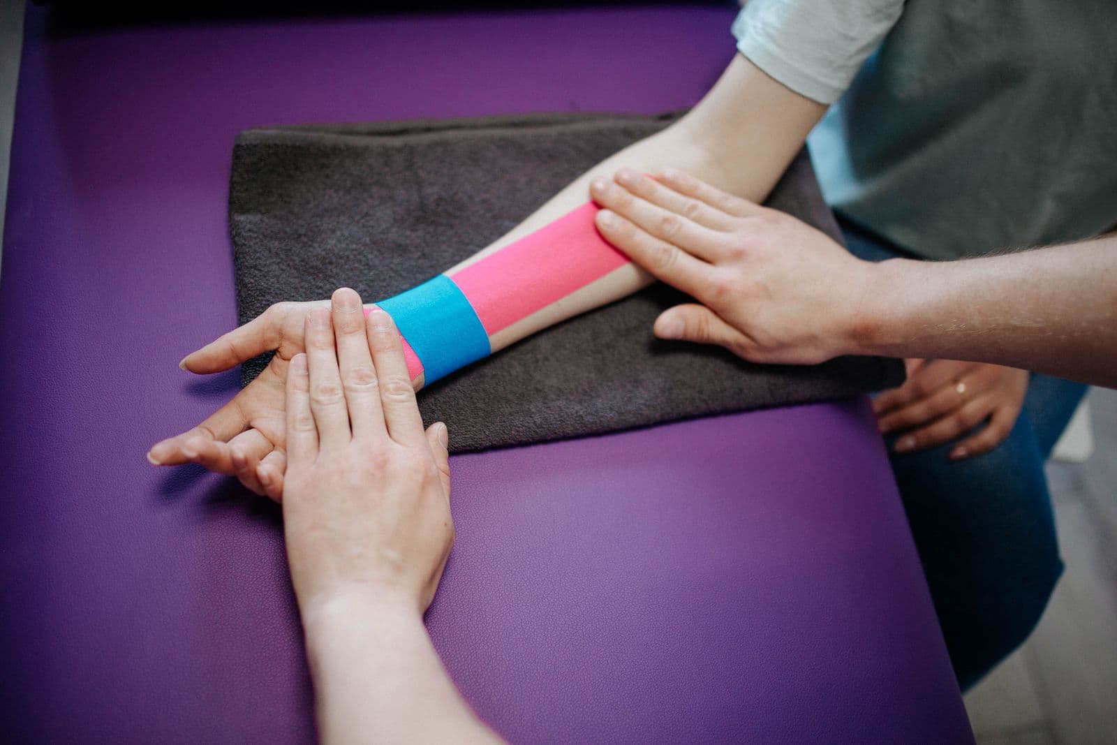Therapist applying kinesiology tape to a patient's forearm