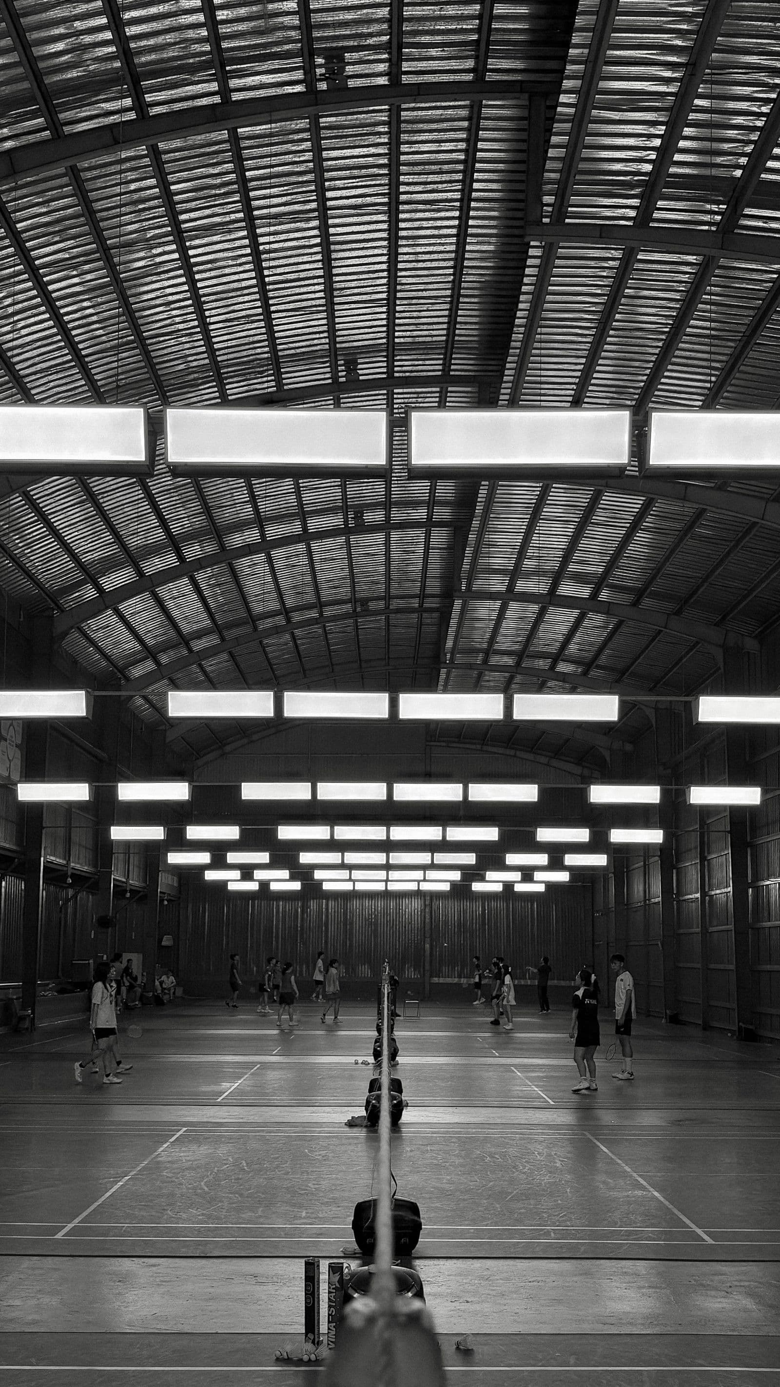 Busy indoor badminton hall with games on multiple courts