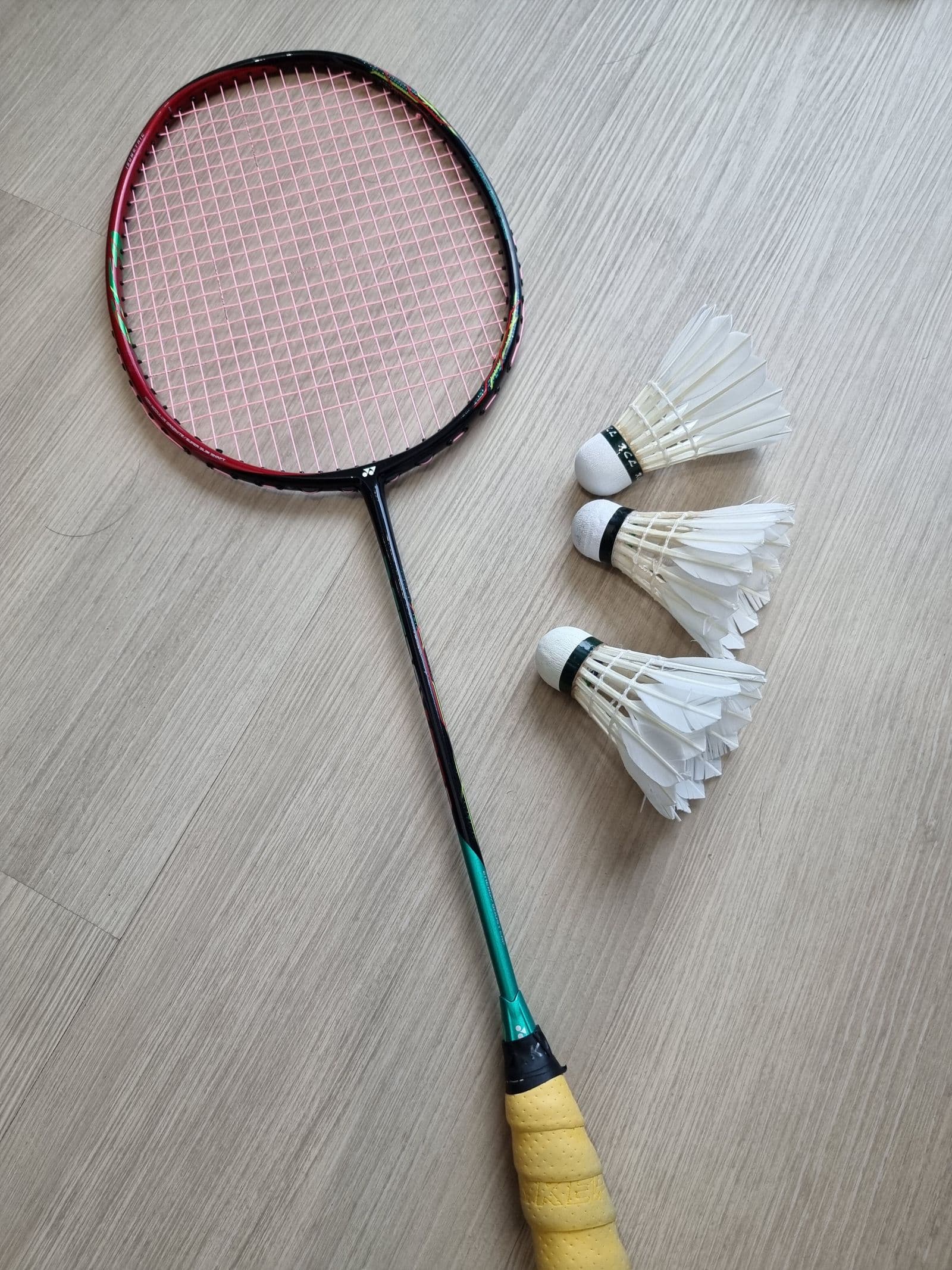 Badminton racket and shuttlecocks on a wooden court floor