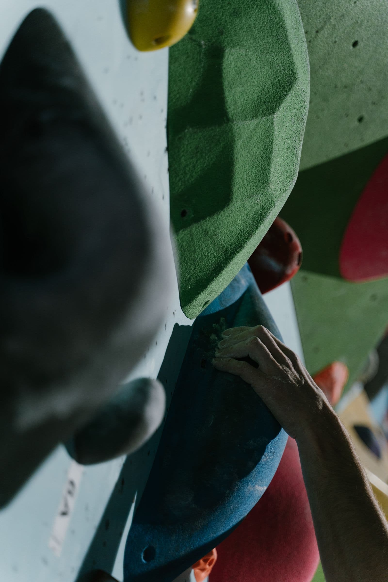 Close-up of a climber's fingers gripping holds on an indoor wall