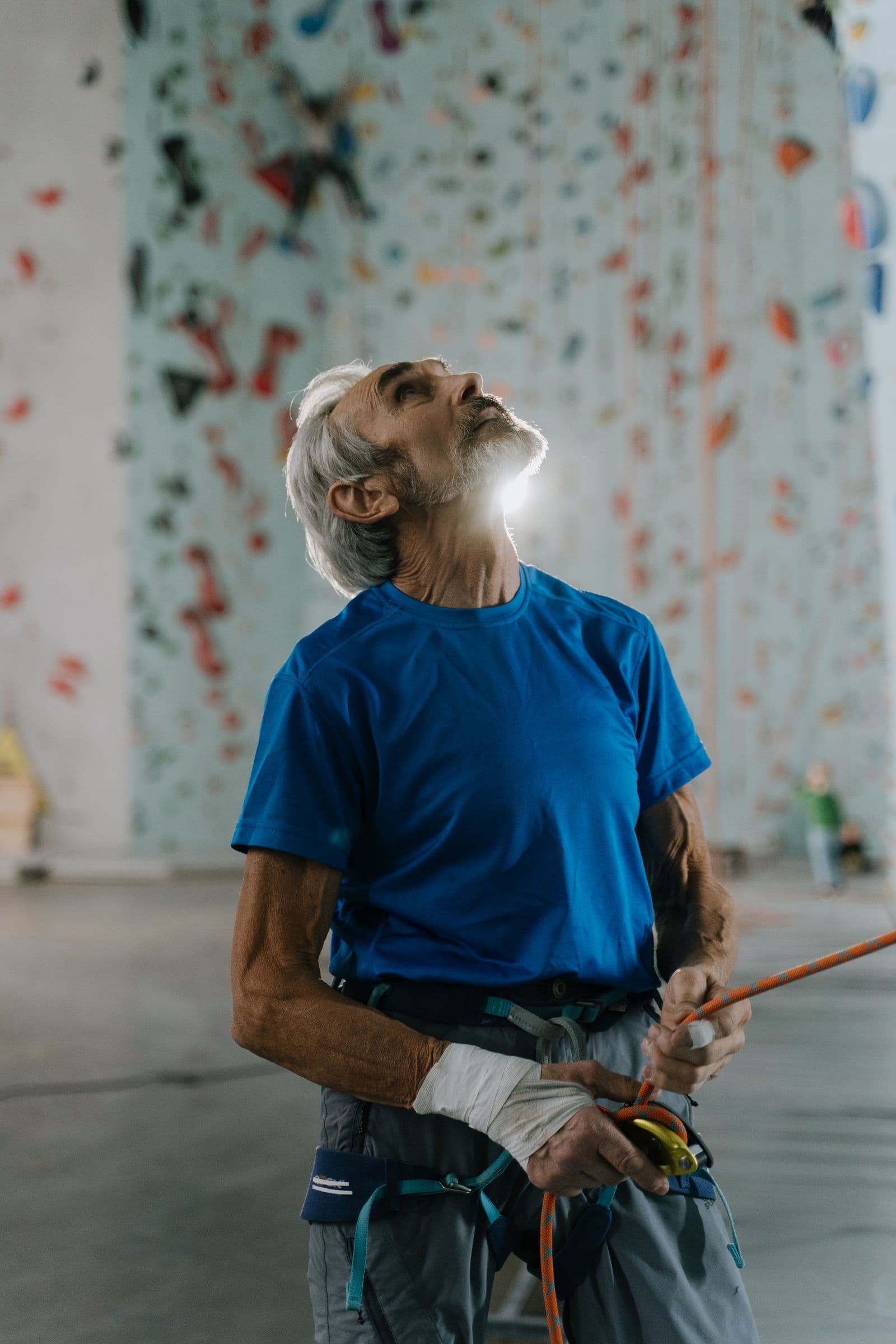 Older climber belaying at an indoor climbing gym