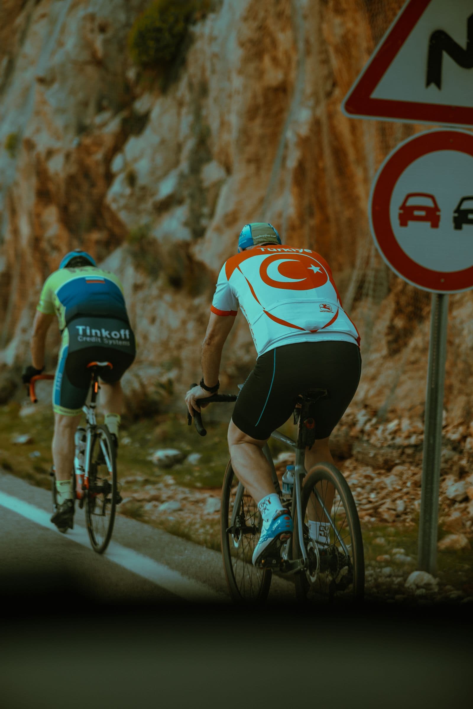 Two cyclists climbing a scenic mountain road