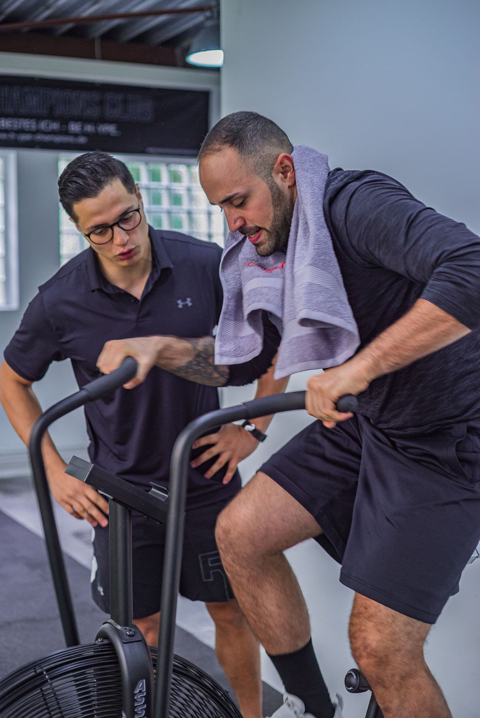 Cyclist training on a stationary bike with an instructor supervising