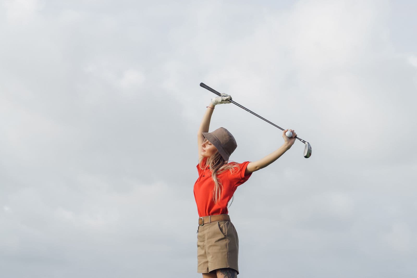 Golfer stretching her back using a golf club