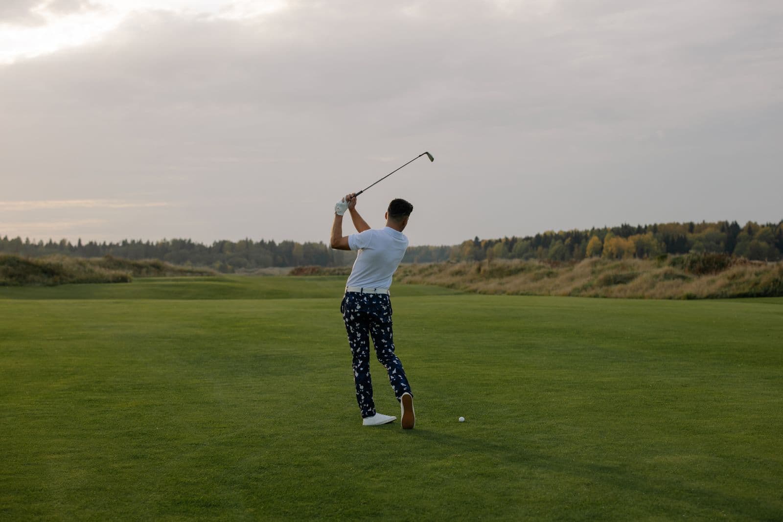 Golfer mid-swing on a course