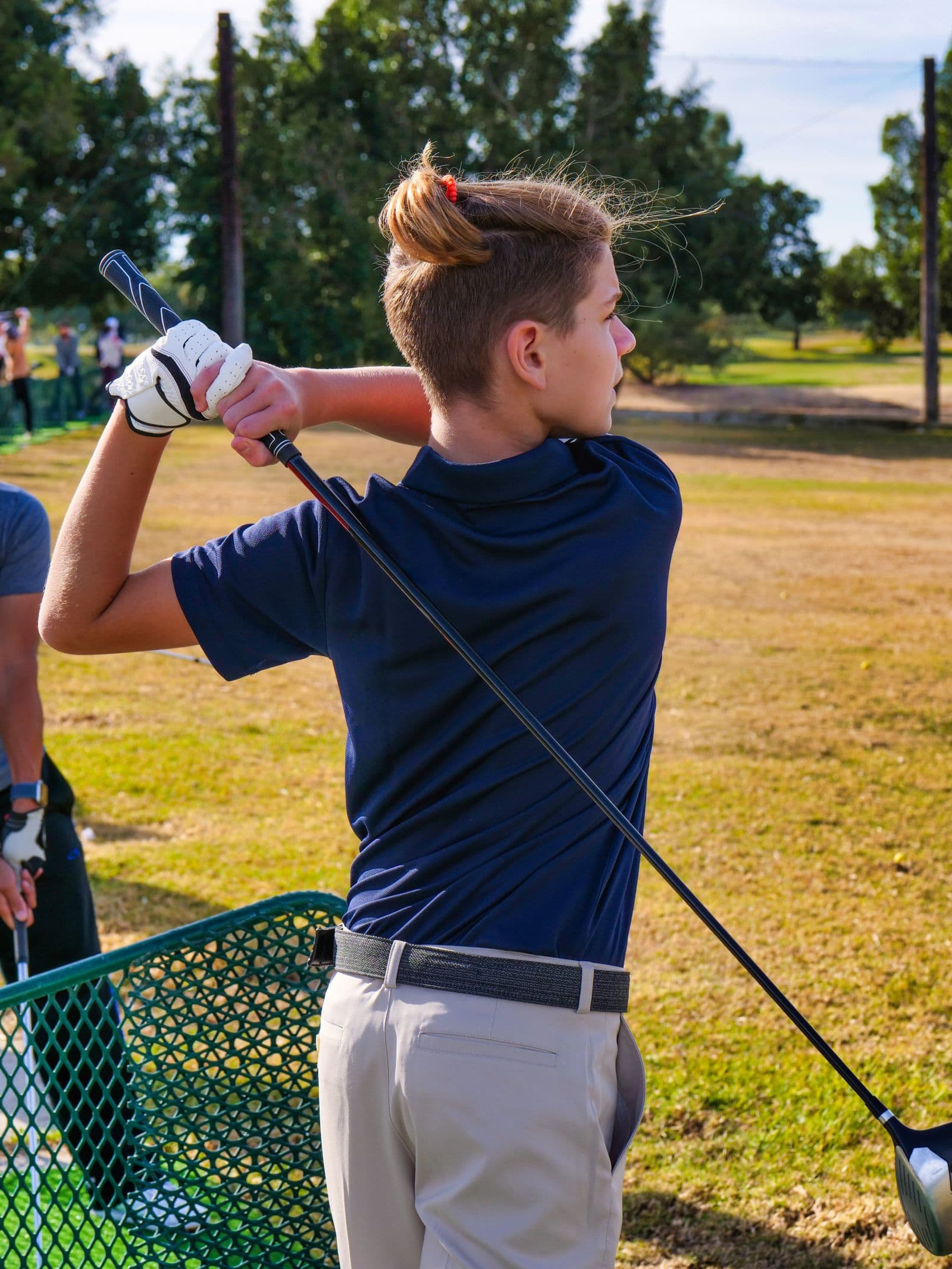 Teenager practicing his golf swing at a driving range