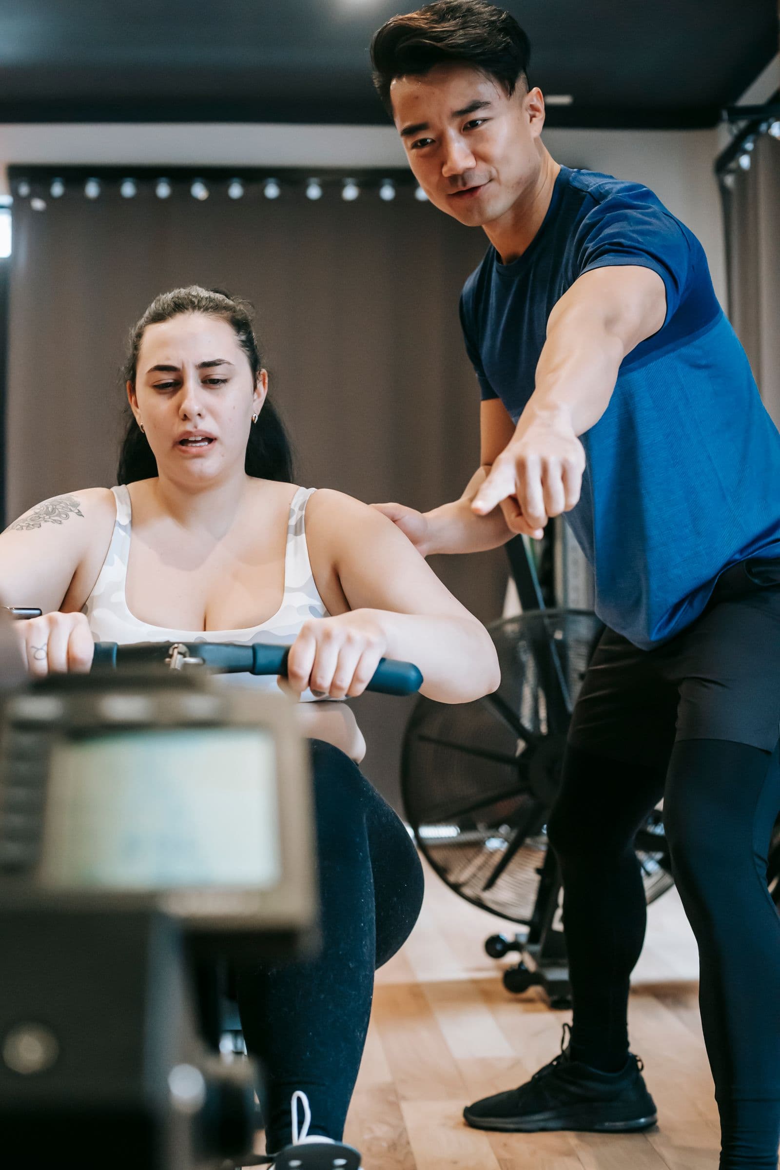 Coach adjusting an athlete's erg setup and screen