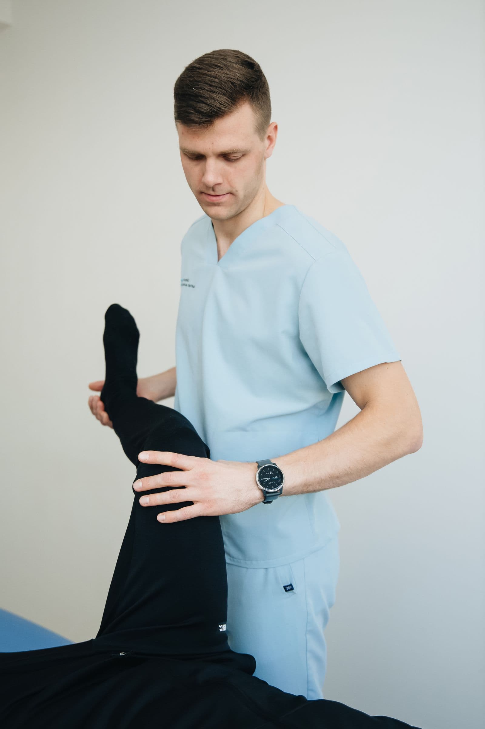 Physical therapist guiding a patient through a leg exercise on a treatment table
