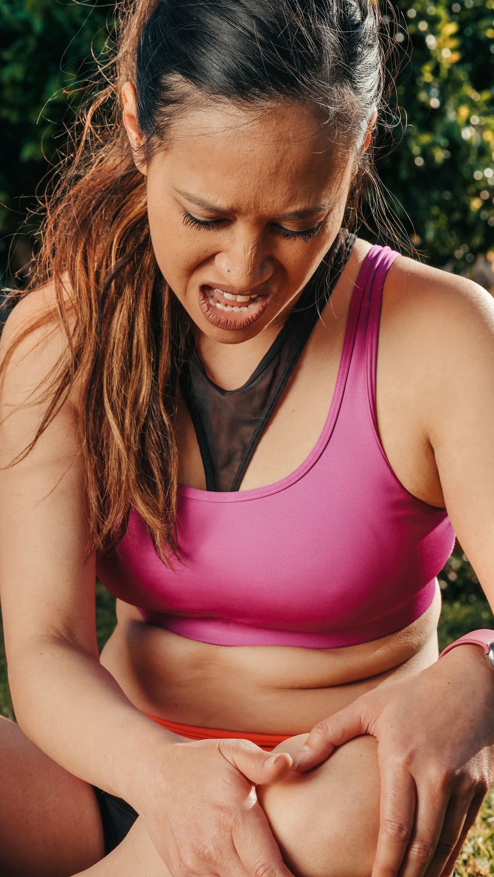 Runner pausing outdoors and holding her knee in pain