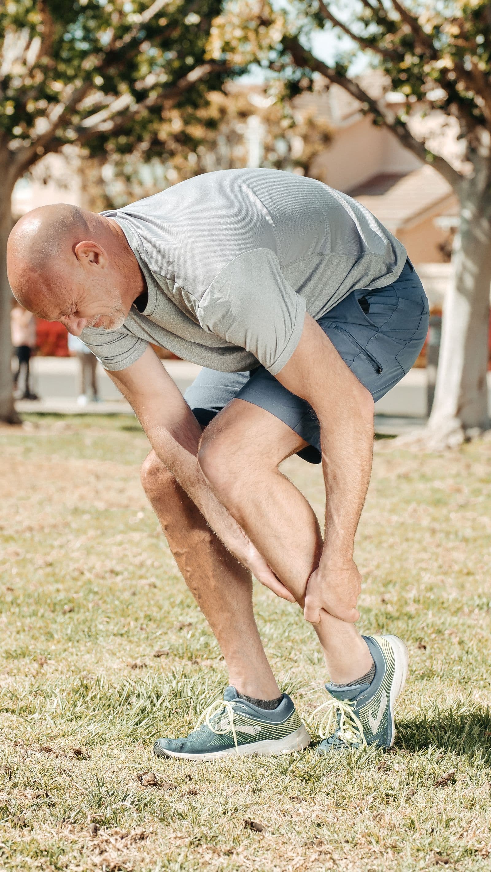 Runner holding his lower leg on a park path
