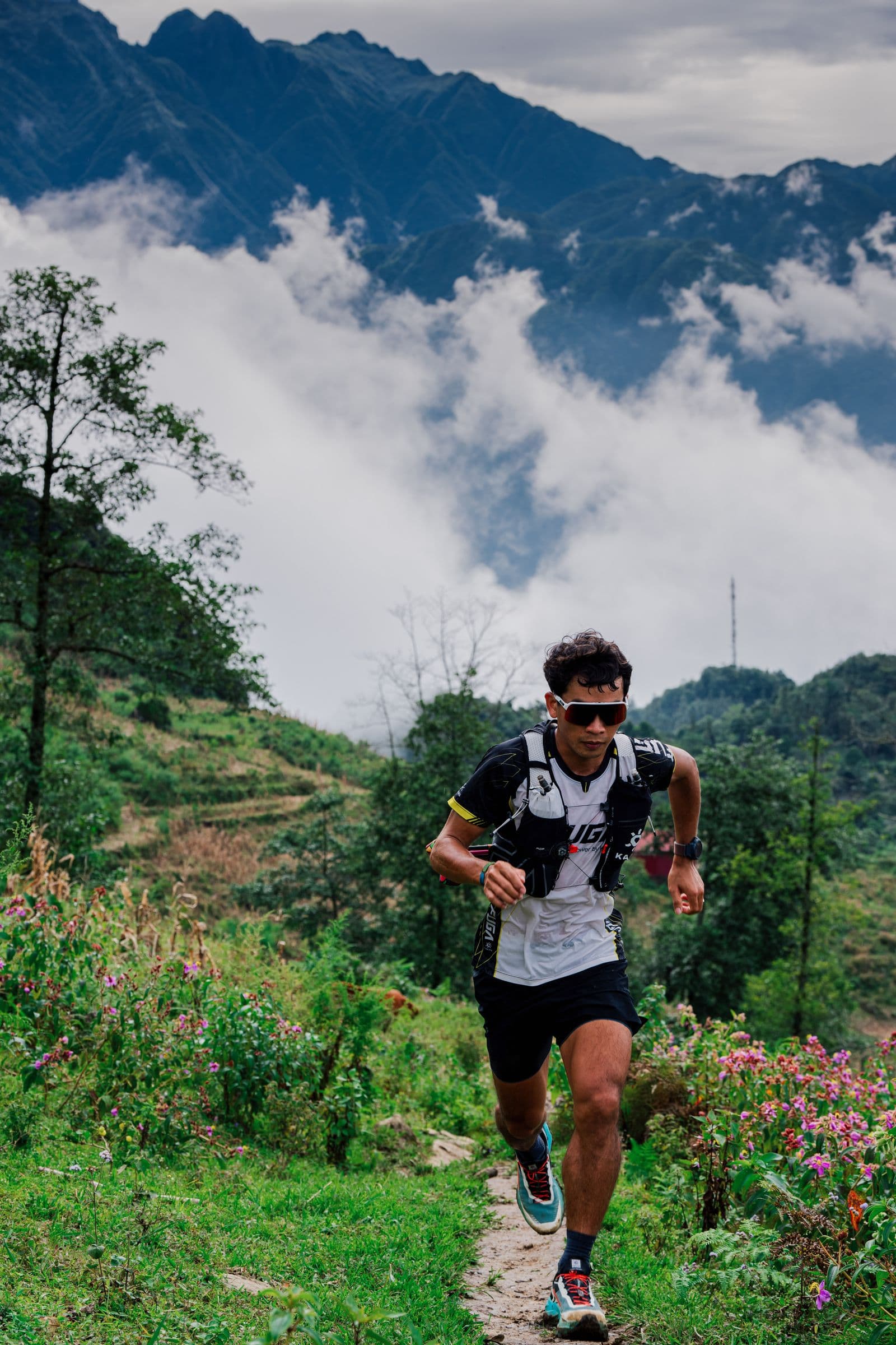 Trail runner crossing mountainous terrain under a dramatic sky