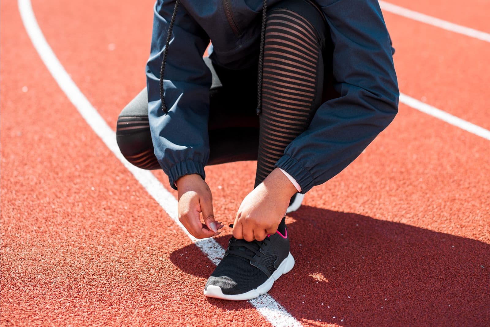 Runner tying a running shoe on a track