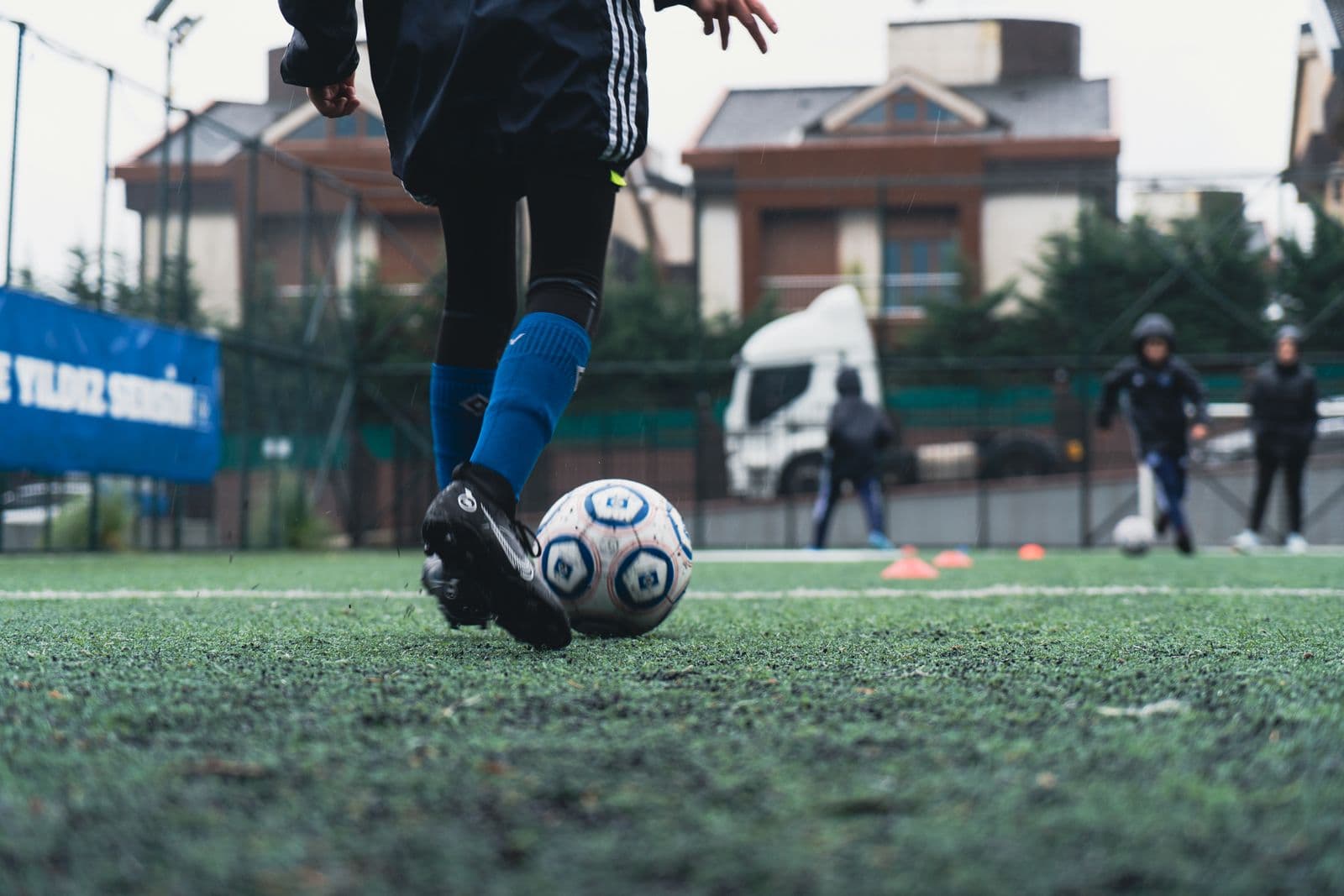 Close-up of a young player's cleats and the ball on grass