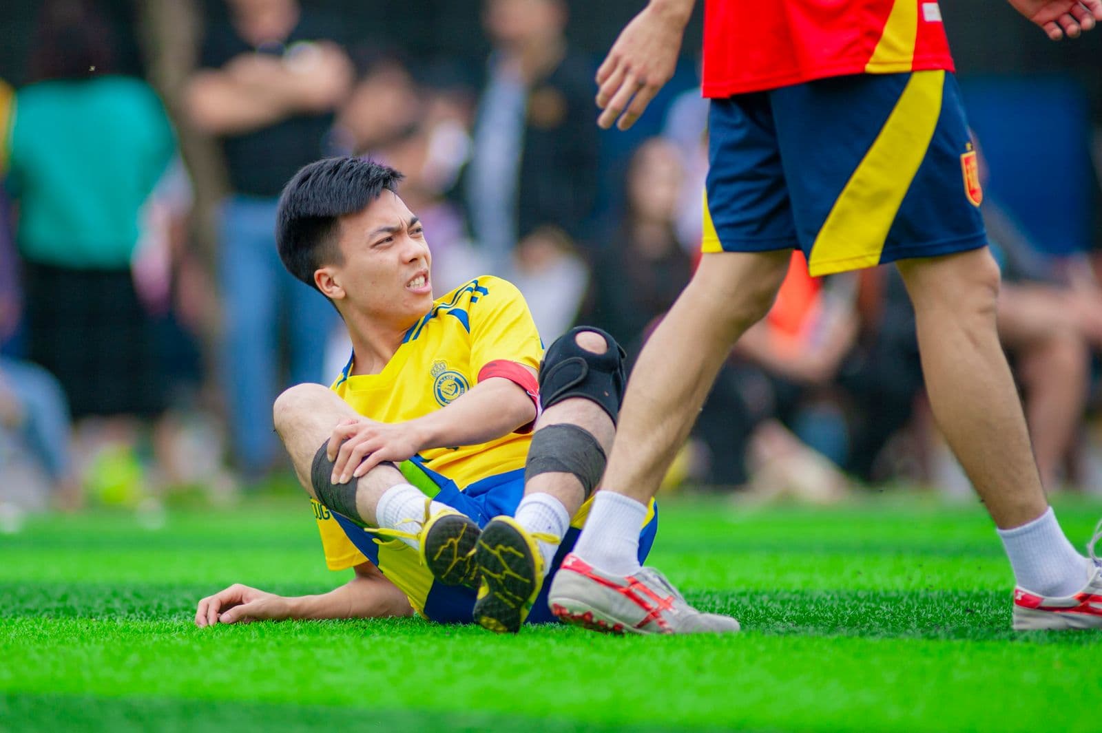 Soccer player on the grass holding his leg during a match