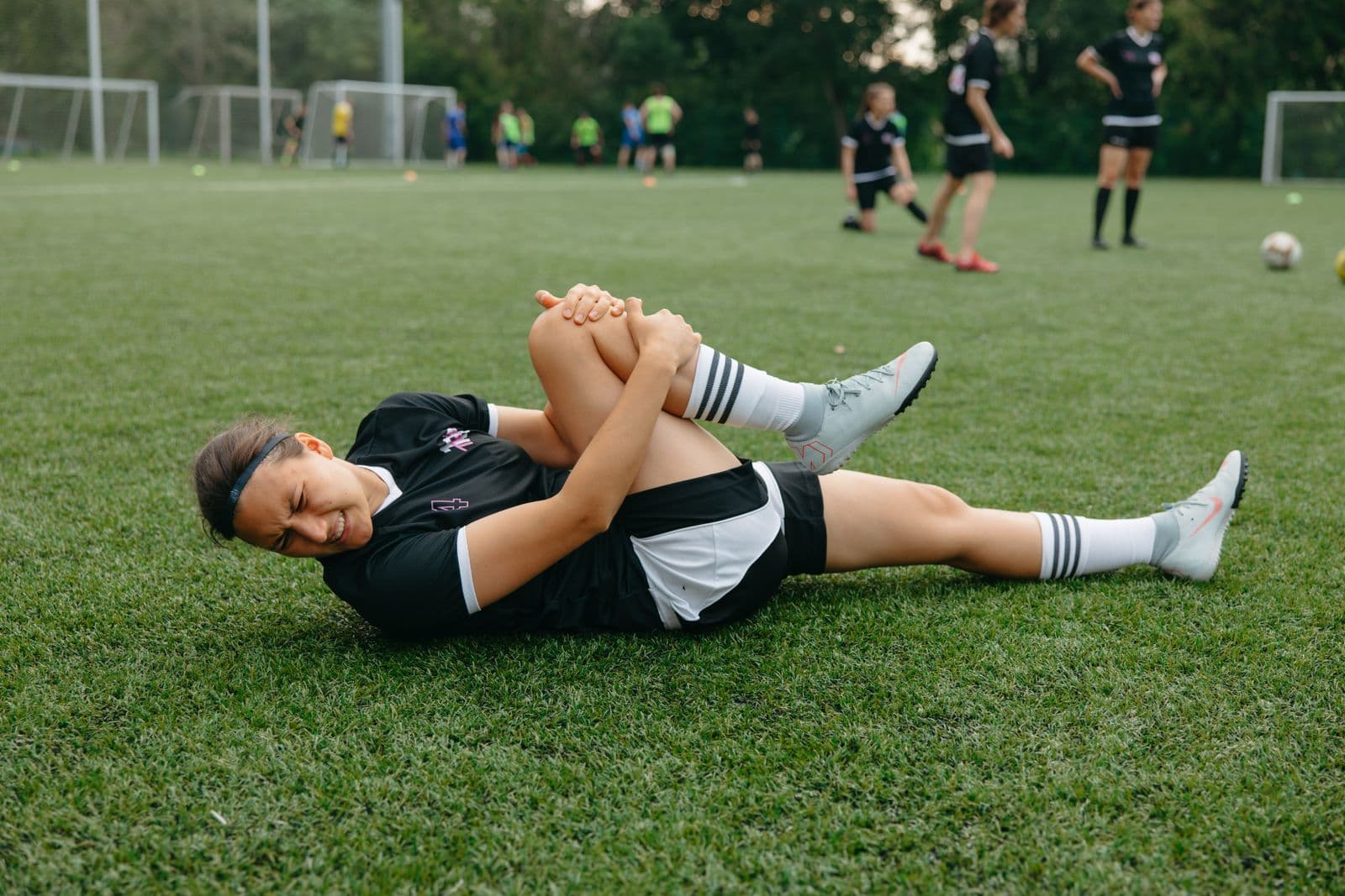 Soccer player on the pitch gripping her injured leg