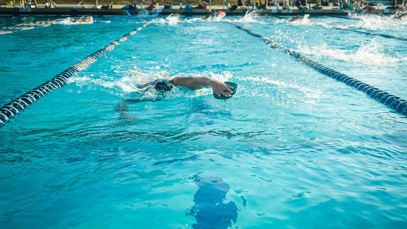 Swimmer training with hand paddles in an outdoor pool