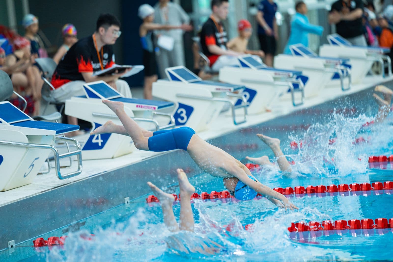 Young swimmers diving off the blocks at a meet