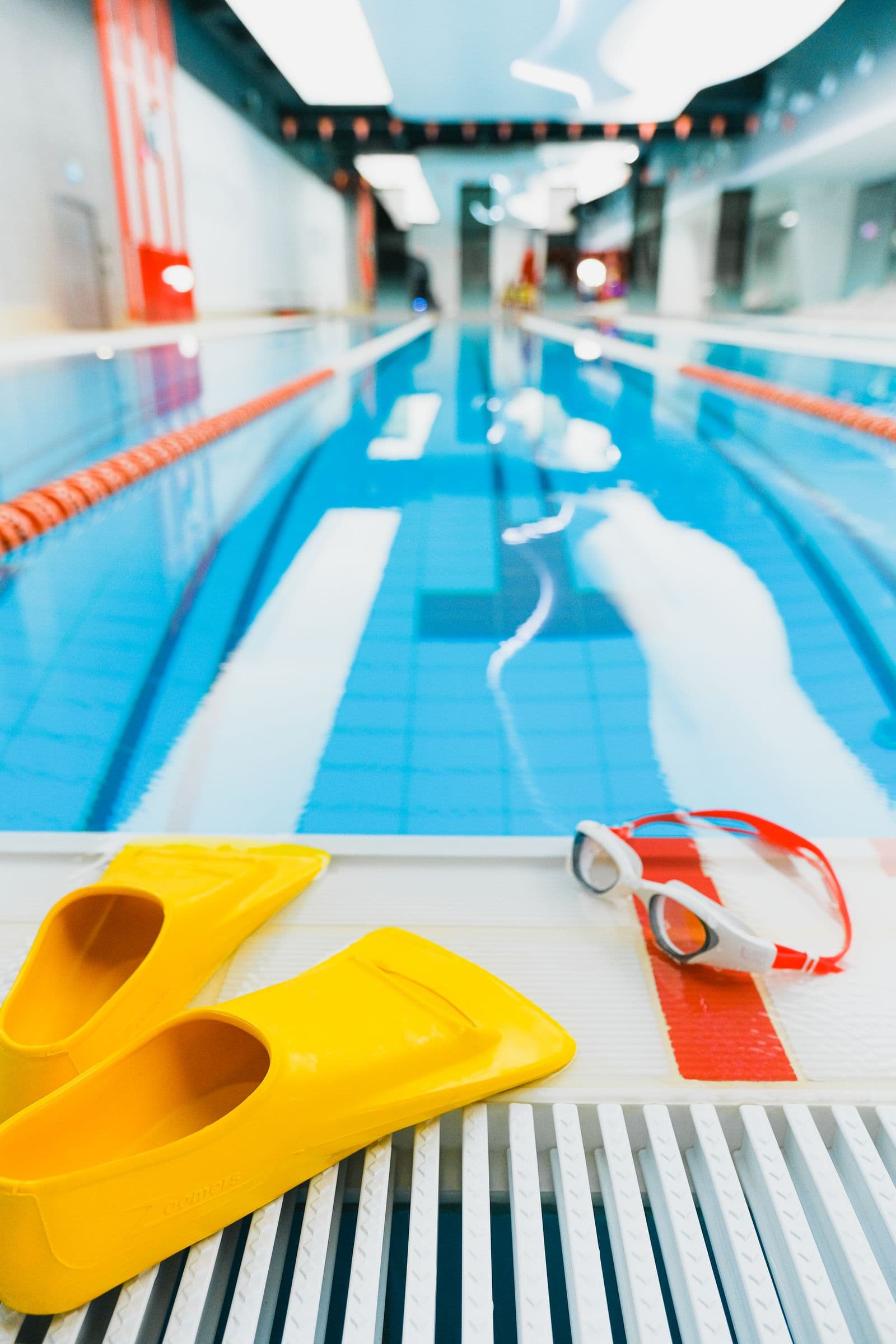 Swim fins and goggles laid out at the edge of a pool