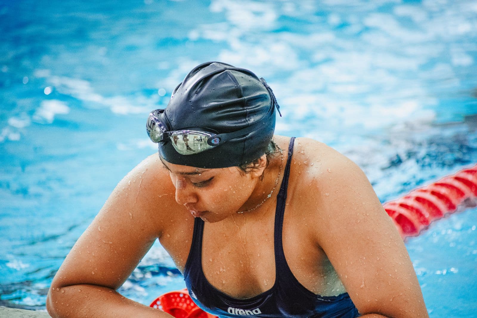 Swimmer in cap and goggles pausing at the poolside