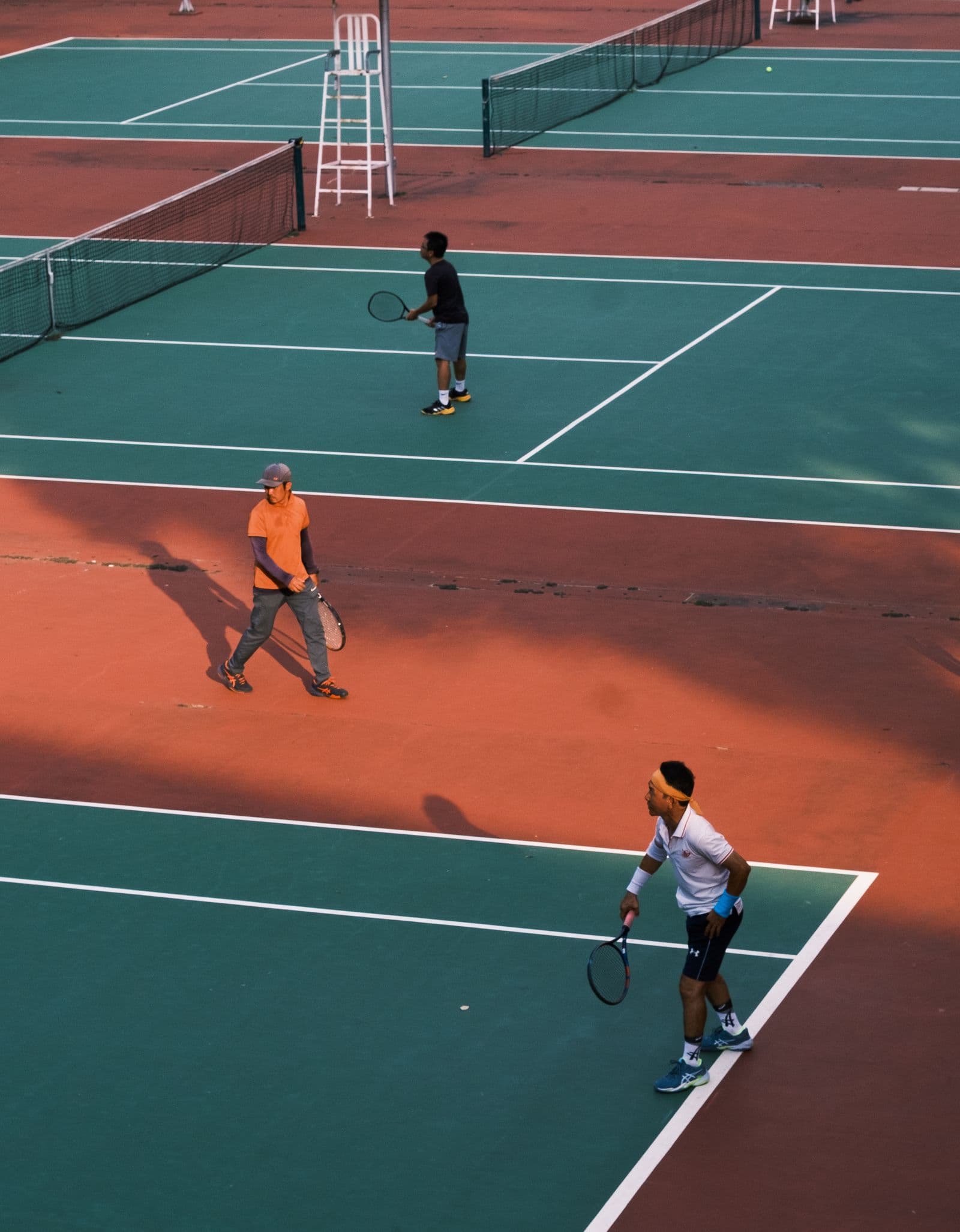 Tennis players on outdoor hard courts on a sunny day