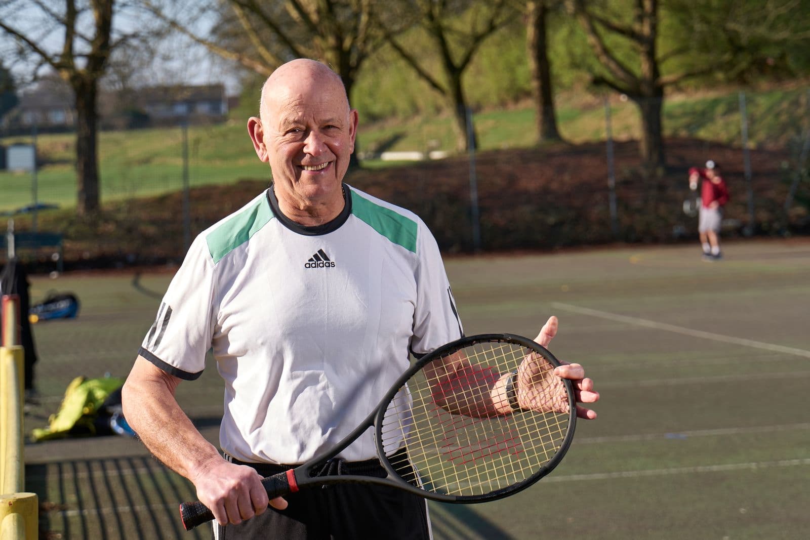 Older adult playing tennis on a sunny outdoor court