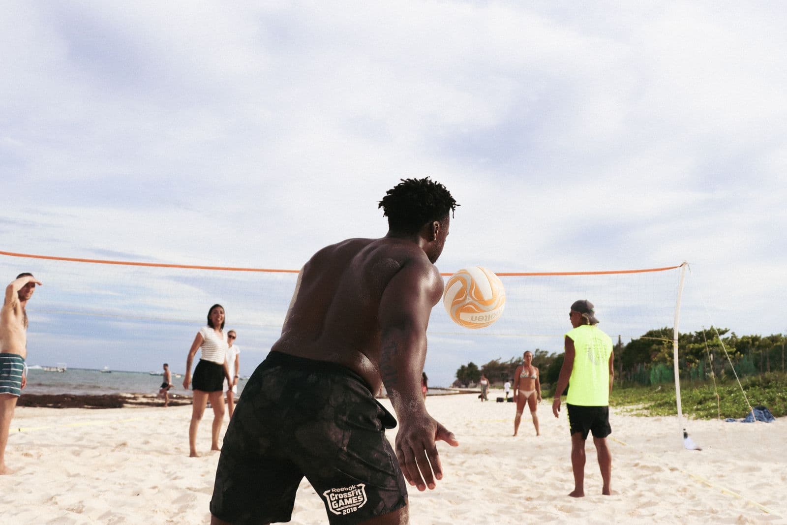 Player arching into a serve on a beach volleyball court