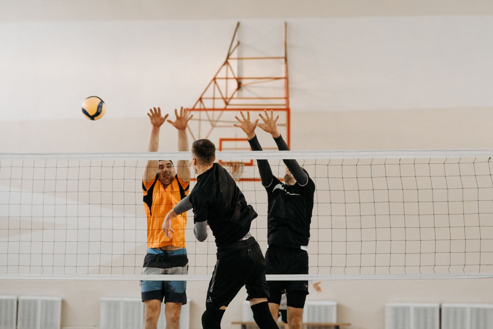 Blockers' hands up at the net against a spike
