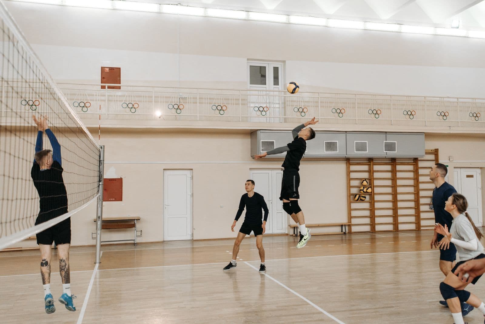 Players mid-rally in an indoor volleyball match